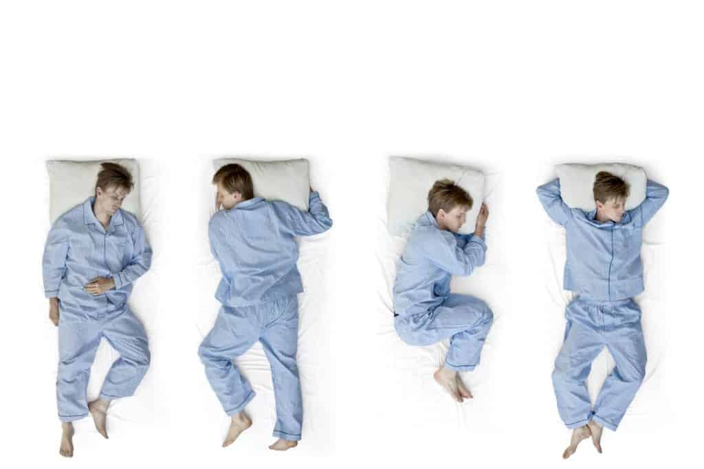 A man tries different sleeping positions in bed.