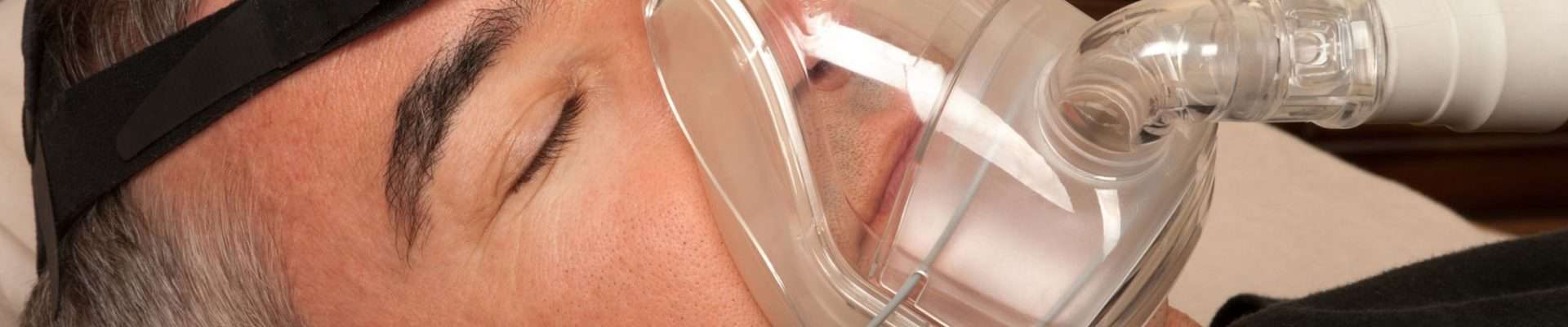Man sleeping with a CPAP device to treat sleep apnea.
