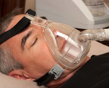Man sleeping with a CPAP device to treat sleep apnea.
