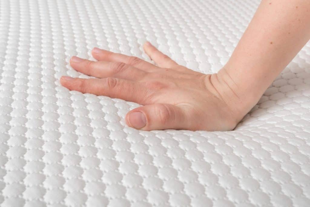 Hand of a woman testing a mattress.