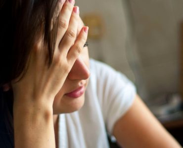 A tired woman holds her head.